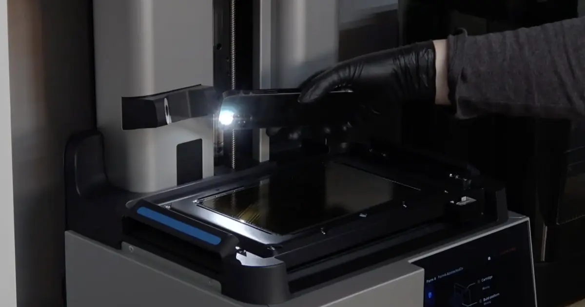 暗い部屋でForm 4のLPU表面に横からスマホのライトを当てて検査している様子