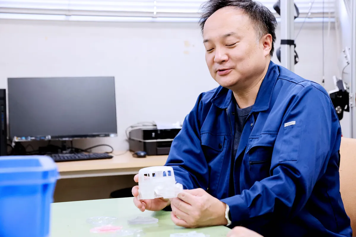 新家教授がクリアレジンで造形した車のモデルを手に取る様子