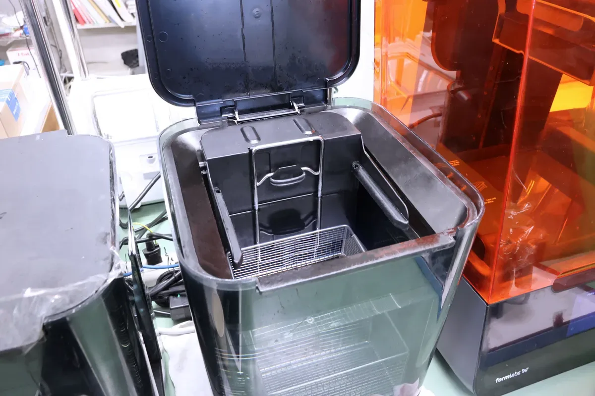 ふたを開けた洗浄機と、横に置かれた洗浄液のタンク