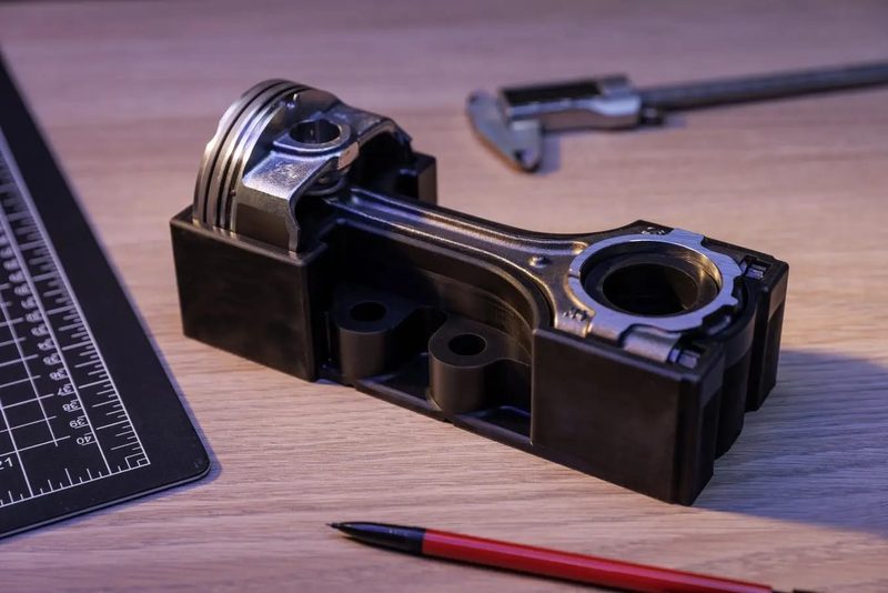 フレキシブル80A で造形した黒い受け台に、金属製のピストンとコンロッドを寝かせて保持したところ