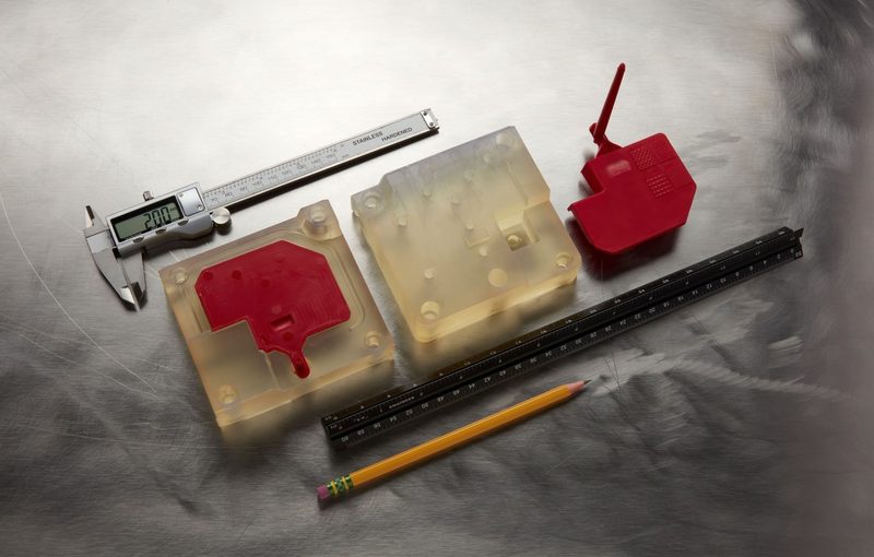 ハイテンプで造形した 2 枚合わせの成形型と、そこから成形した赤い部品