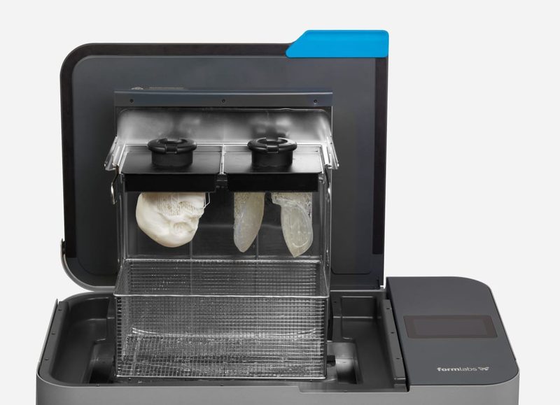 Form Wash L の庫内。プラットフォームマウント 2 基に頭蓋骨の模型と透明な造形品が吊り下がり、その下に金属製の洗浄バスケットがある