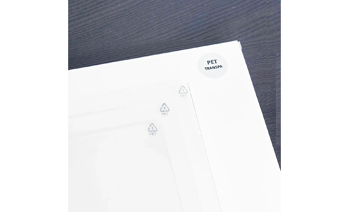 重ねた PET シートの角の接写。角に PET のリサイクルマークと、PET と書かれた丸いラベルが見える